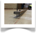 Once the floor has been marked and straight lined by laser, studs are fixed into the floor to support the track ready for leveling.